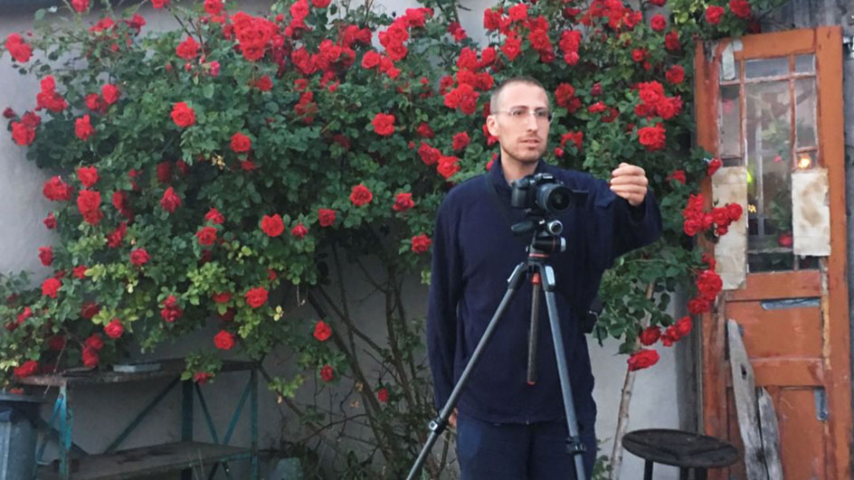 Sebastian Johansson Micci med kamera framför en rosenbuske. Foto: Tuva Björk.