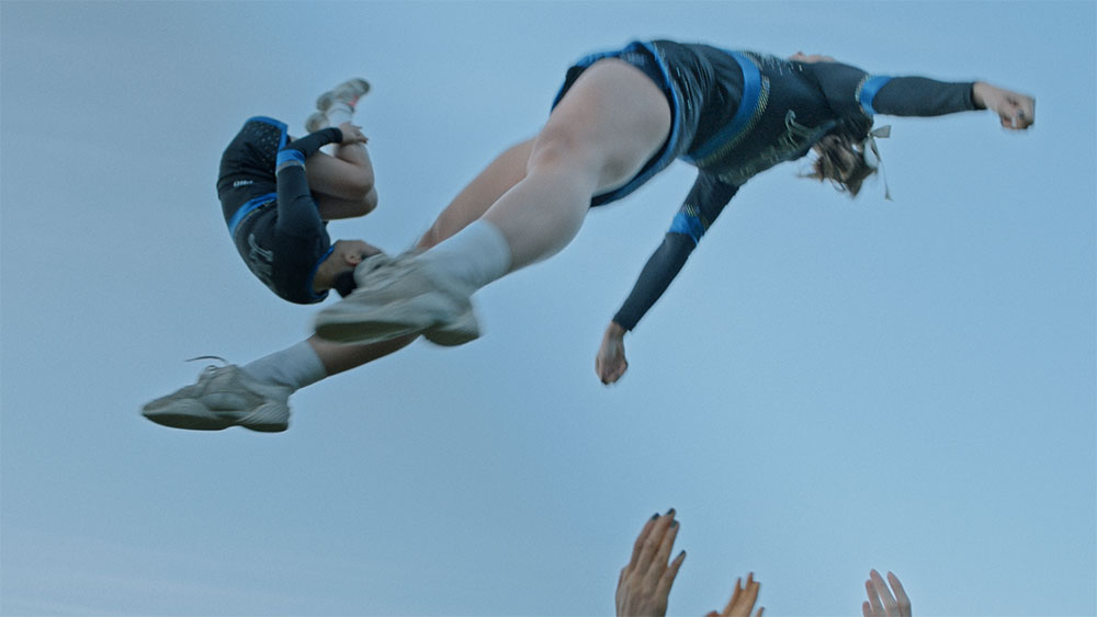 Stillbild från Power Jaguars. Foto: Niklas Panthell. Syntolkning: Två cheerleaders gör volter i luften.