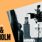 Syntolkning. Svartvit bild på filmfotograf med kamera med Stockholms stadshus i bakgrunden.
