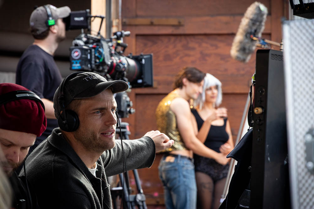 Regissör tittar på monitor medan en kamera i bakgrunden filmar två skådespelare.