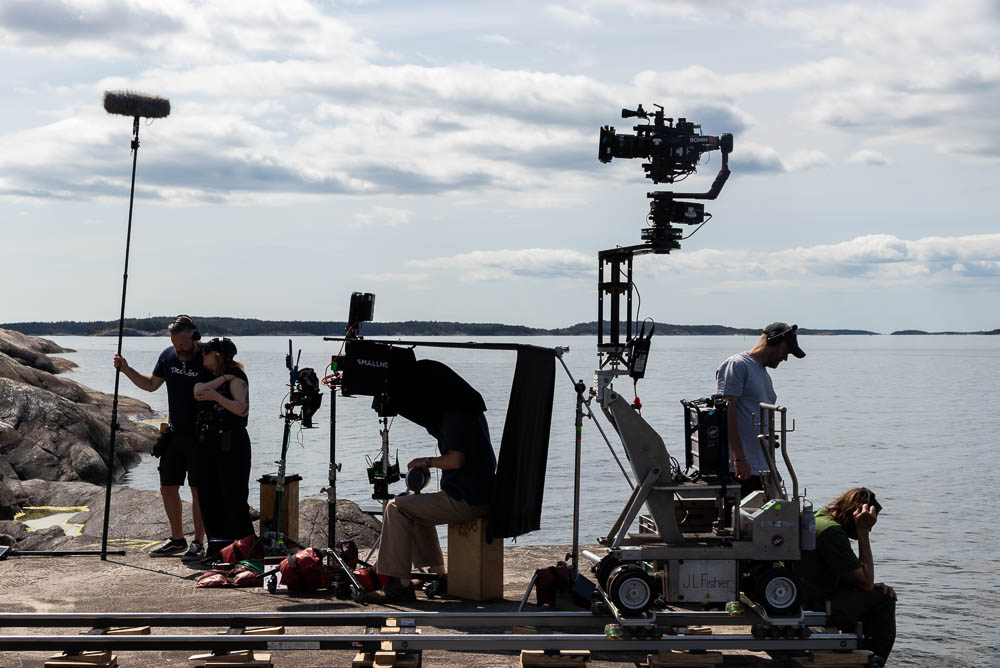 Filmteam arbetar på en brygga med skärgården i bakgrunden.