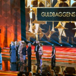 Flera glada personer på scenen med texten 