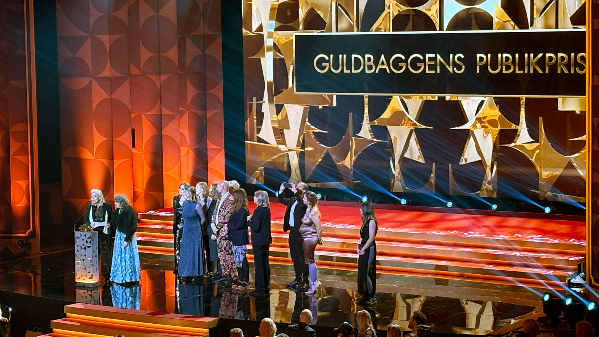 Flera glada personer på scenen med texten 