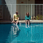 En man och en kvinna sitter bredvid varandra på en poolkant.