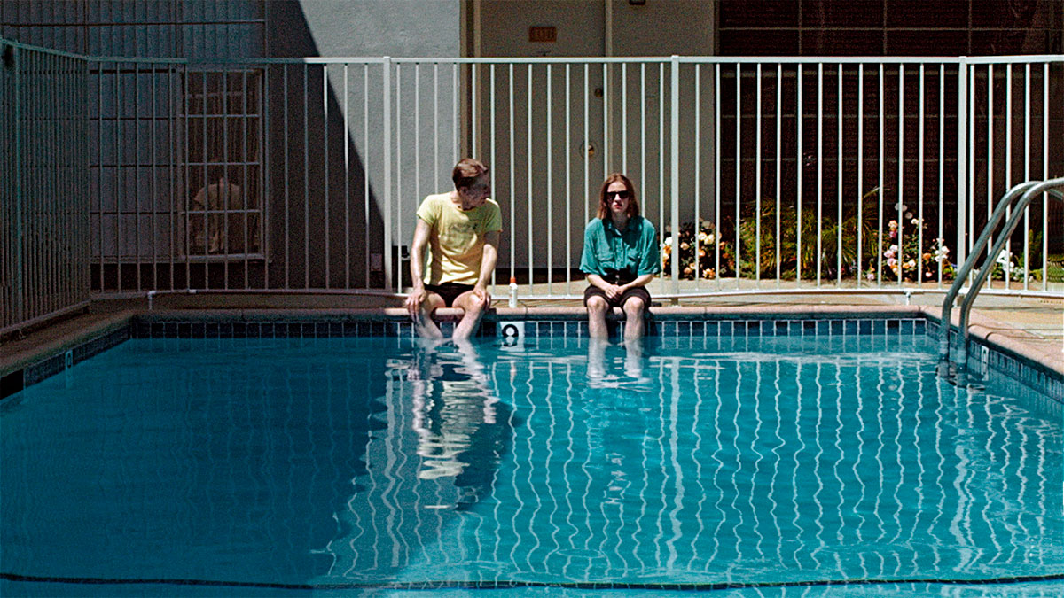 En man och en kvinna sitter bredvid varandra på en poolkant.