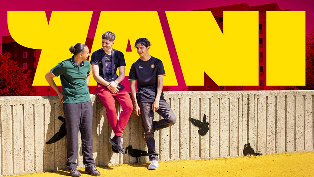 Tre killar vid en mur med texten 