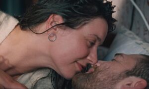 Stillbild ur SLOW. Greta Grineviciute och Kęstutis Cicėnas ligger i en säng och kysser varandra. Foto: Laurynas Bareiša.
